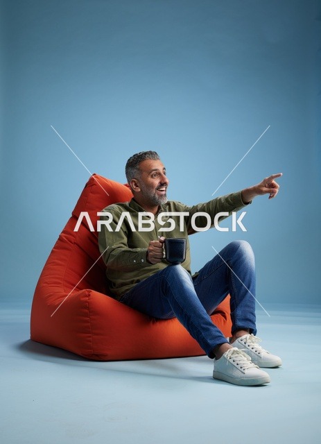 رجل سعودي على كنبة كيس مع فنجان قهوة