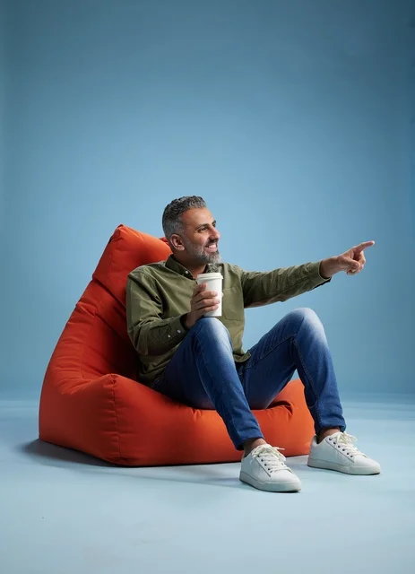 Saudi Man on Red Beanbag Pointing with Coffee Cup