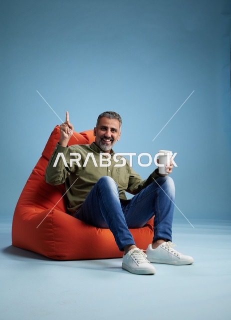 رجل سعودي على كنبة كيس مع كوب قهوة
