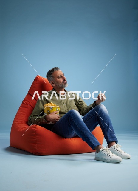 رجل سعودي يستمتع بأكل الفشار على كنبة كيس