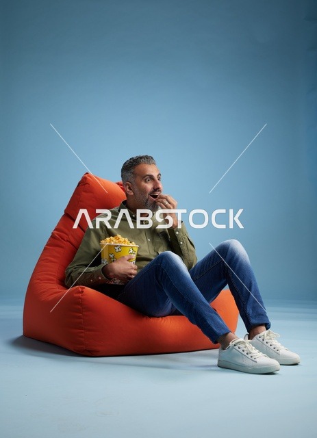 رجل سعودي يأكل الفشار على كنبة كيس