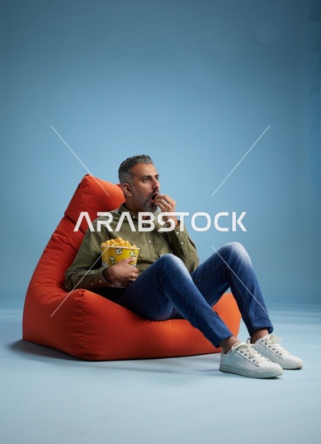 Saudi Man Eating Popcorn on Orange Bean Bag