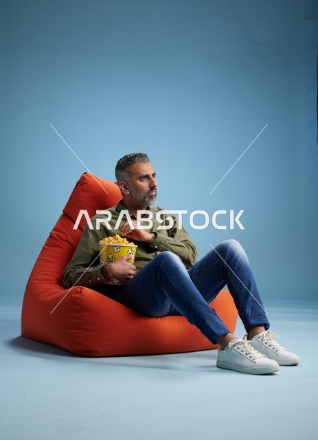 رجل سعودي يأكل الفشار على كنبة كيس