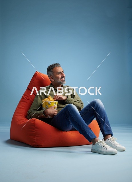 رجل سعودي يأكل الفشار على كنبة كيس حمراء