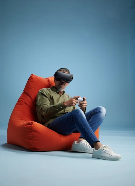 رجل يستخدم سماعة الواقع الافتراضي على كرسي برتقالي