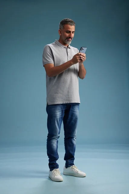 Arab Man Using Smartphone on Blue Studio Background