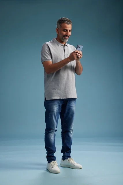 رجل سعودي يستخدم الهاتف الذكي بخلفية زرقاء