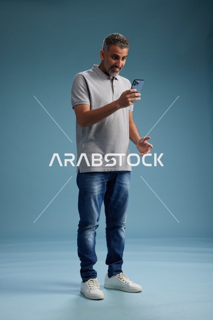 رجل عربي في منتصف العمر يستخدم الهاتف الذكي في الاستوديو