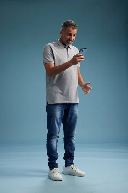 رجل عربي في منتصف العمر يستخدم الهاتف الذكي في الاستوديو