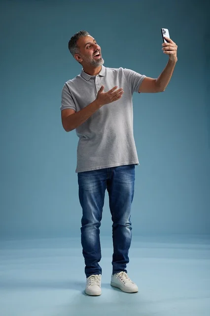 Arab Man Using Smartphone on Blue Studio Background
