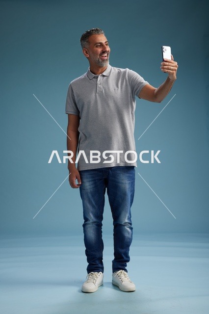 Smiling Arab Man Taking Selfie on Smartphone in Studio