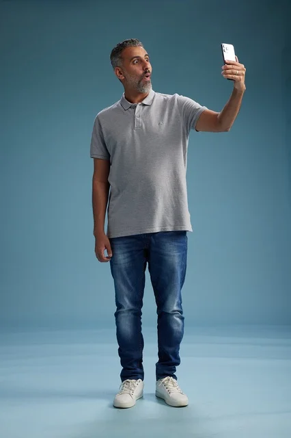 رجل عربي متفاجئ يحمل هاتفاً ذكياً بخلفية زرقاء