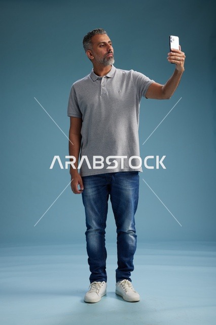 رجل عربي يلتقط سيلفي في استوديو خلفية زرقاء