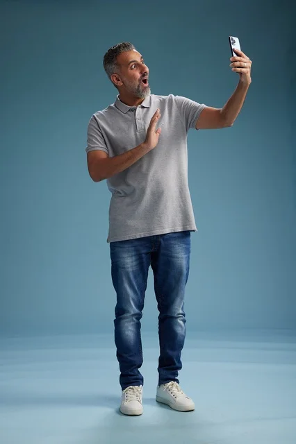 رجل عربي مندهش يستخدم الهاتف الذكي في الاستوديو