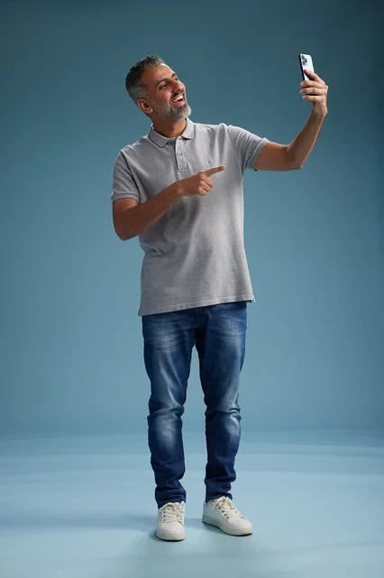 Middle-aged Arab Man Pointing at Smartphone in Studio