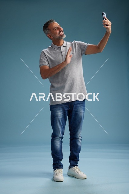 Middle Aged Arab Man Using Smartphone in Blue Studio
