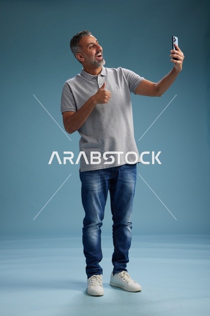 رجل عربي يلتقط سيلفي بإيماءة الإبهام في الاستوديو