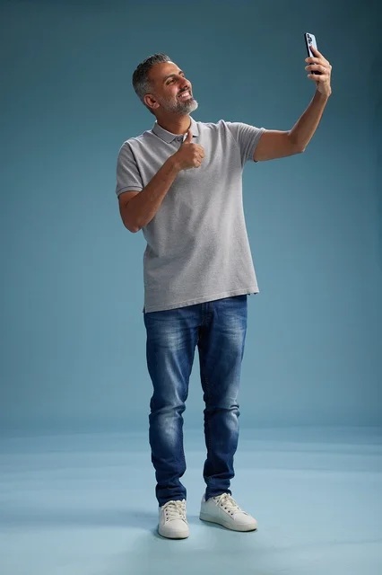 رجل عربي يلتقط صورة سيلفي بإشارة الإبهام في الاستوديو