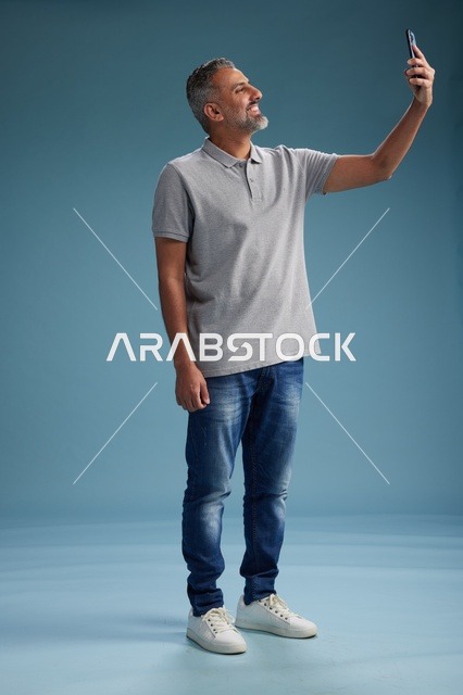 رجل عربي يلتقط صورة سيلفي بالهاتف في استوديو