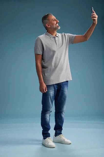 رجل عربي يلتقط صورة سيلفي بالهاتف في استوديو