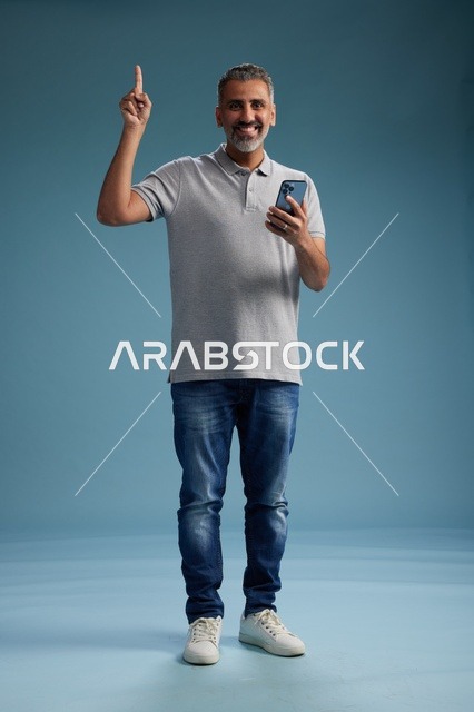 رجل سعودي يحمل هاتف ذكي ويشير للأعلى