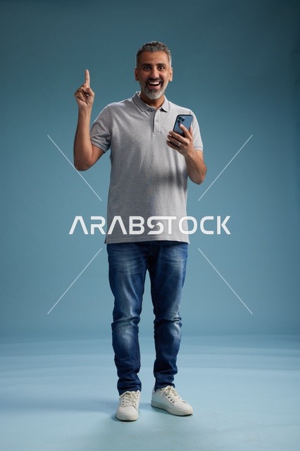 رجل عربي يشير للأعلى مع هاتف ذكي في الاستوديو