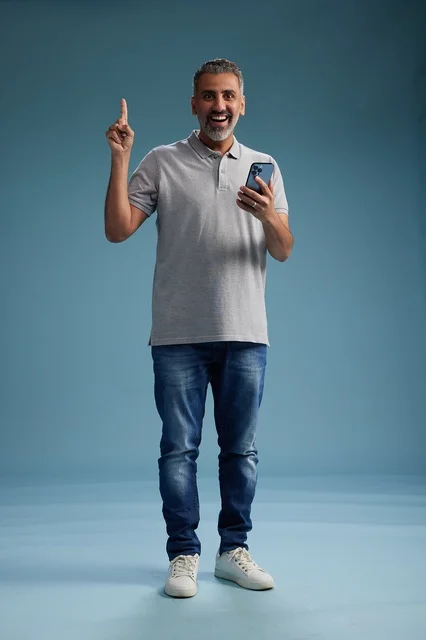 Arab Man Pointing Up with Smartphone in Studio