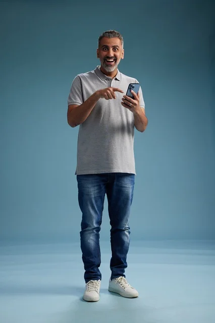 رجل عربي متحمس يشير إلى هاتف ذكي في استوديو