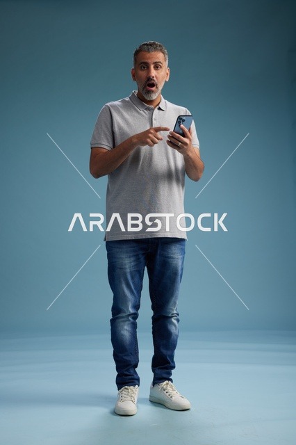 رجل عربي متفاجئ يشير إلى شاشة الهاتف الذكي