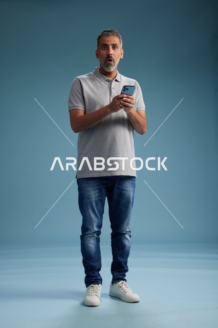 رجل عربي بتعبير مصدوم يمسك هاتف ذكي