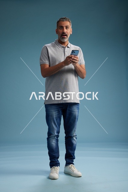 رجل عربي مندهش يحمل هاتف في استوديو