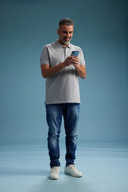 Arab Man Using Smartphone on Blue Studio Background