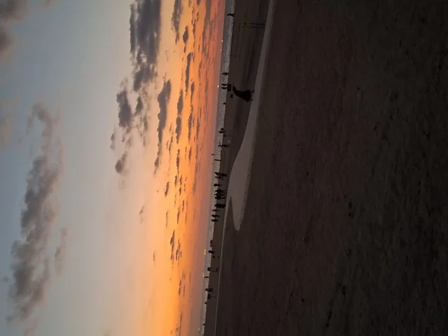 مشهد الغروب الخلاب على الشاطئ مع ظلال الأشخاص