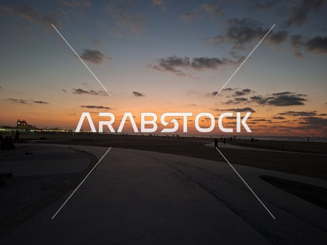 ممشى الشاطئ العام وأفق المدينة الساحلية وقت الغروب