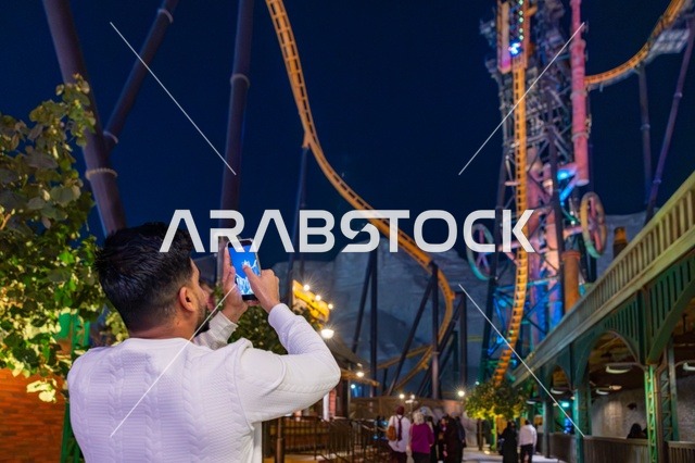 رجل يلتقط صورة لقطار الملاهي في القدية سيكس فلاجز