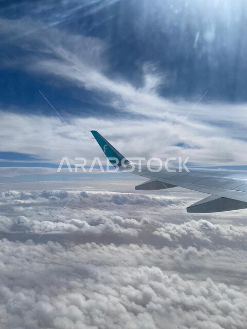 صورة جمالية مقربة لطائرة فلاي ناس تطير بين الغيوم ، طائرة تطير بالسماء الزرقاء بين السحب البيضاء في النهار
