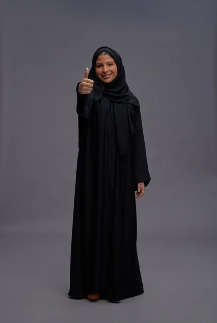 امرأة سعودية بعباءة سوداء تعطي علامة الإبهام