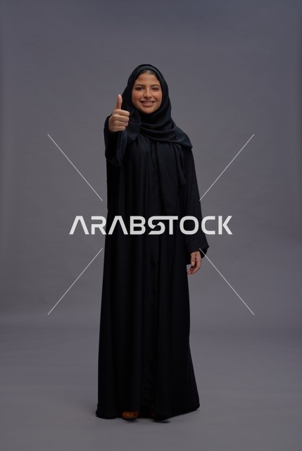 امرأة سعودية بعباءة سوداء مع إيماءة الإبهام للأعلى
