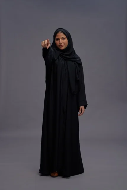 امرأة سعودية ترتدي عباءة سوداء وتشير بإصبعها للكاميرا