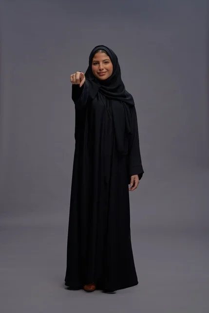 امرأة سعودية بالعباءة السوداء تشير إلى الكاميرا