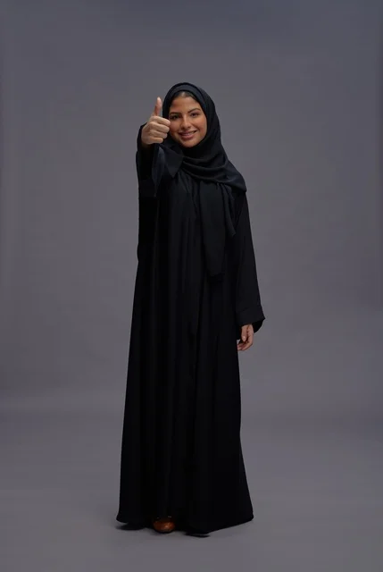 امرأة سعودية بعباءة سوداء ترفع علامة الإبهام