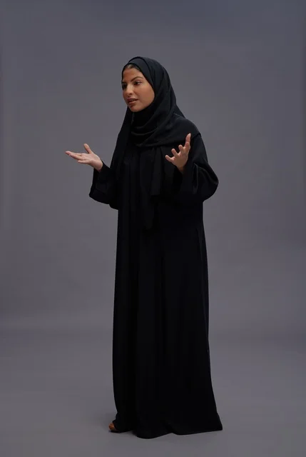امرأة سعودية بالعباءة السوداء تتفاعل في الاستوديو