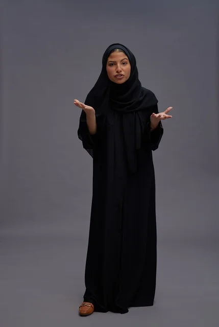 امرأة سعودية بعباءة سوداء تعبر بإيماءات في استوديو