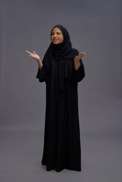 امرأة سعودية بعباءة سوداء في الاستوديو مع إيماءات