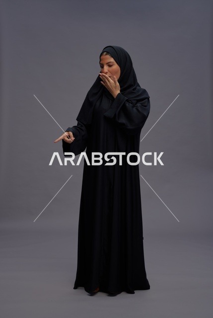 Surprised Saudi Woman in Traditional Abaya Pointing Down