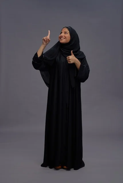 امرأة سعودية بالعباءة السوداء تشير للأعلى