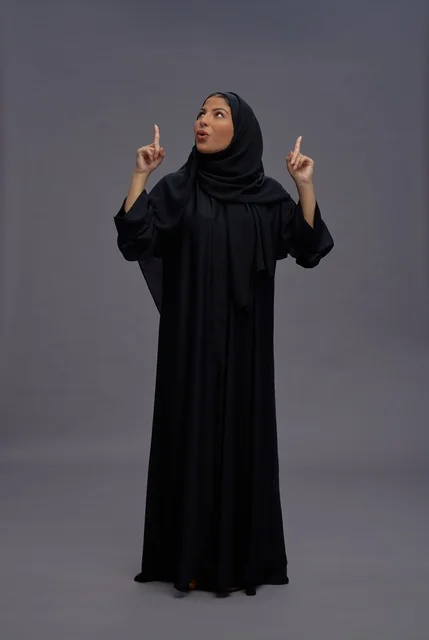 امرأة سعودية بعباءة تقليدية تشير إلى الأعلى