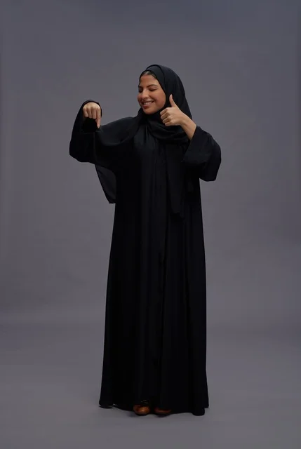 امرأة سعودية بالعباءة التقليدية تشير بعلامة الإعجاب