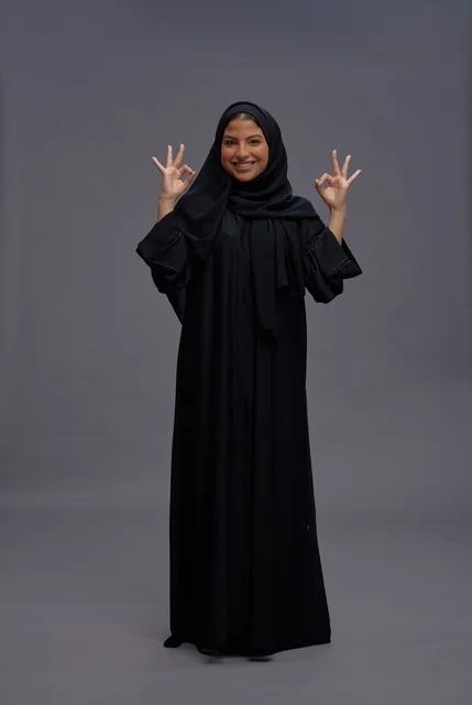 امرأة سعودية بالعباءة التقليدية تقوم بعلامة الموافقة