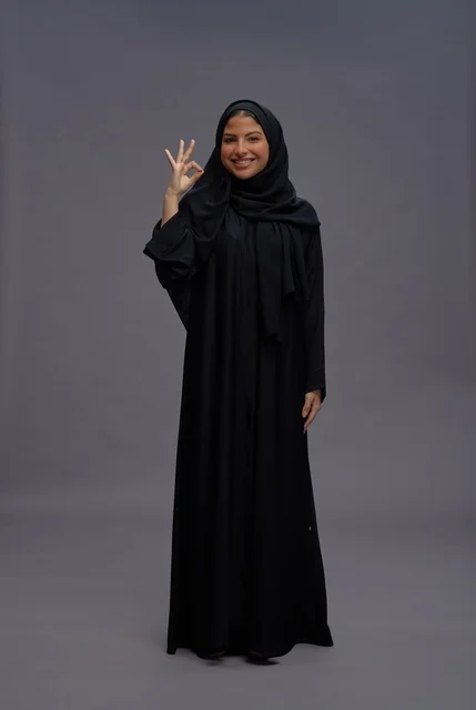 امرأة سعودية بعباءة سوداء تقليدية تشير بعلامة موافق